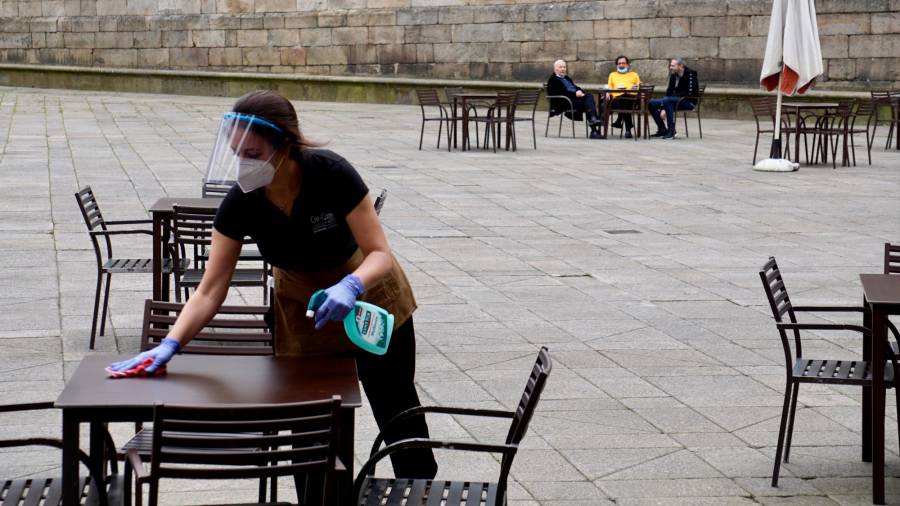 Unha camareira desinfecta unha mesa da terraza dun bar na praza da Quintana. Foto: F.Blanco