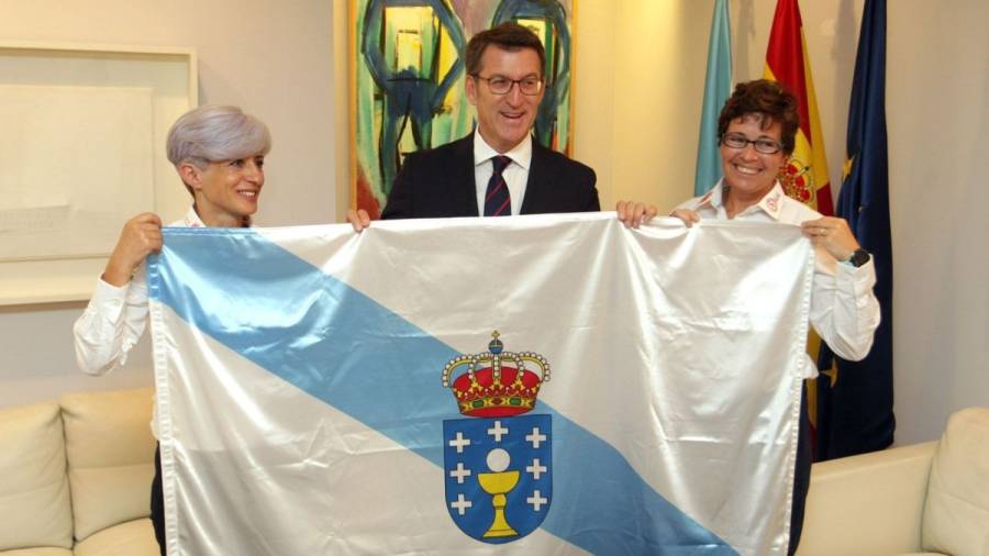 Feijóo entrega una bandera de Galicia a las dos gallegas que participarán  en una expedición al
