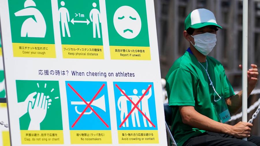 CONSEJOS Un voluntario en Tokio junto a un cartel con medidas para frenar el virus. Foto: DPA Europa Press 