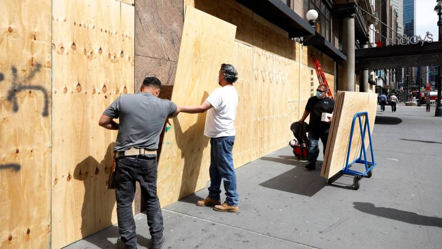 Operarios de los almacenes Macy’s de Nueva York tapan los escaparates rotos. Foto: Efe
