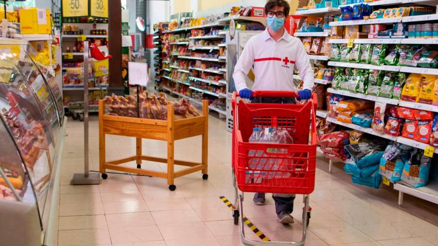 COMPRA. Un voluntario de la Cruz Roja abasteciéndose de alimentos en un supermercado. Foto: EFE / C. Cladera 