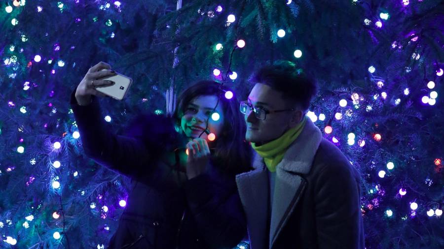 Una pareja rumana se hace un selfie con las luces azules de un árbol de Navidad en Bucharest. (Autor, Robert Ghement. Fuente EFE)