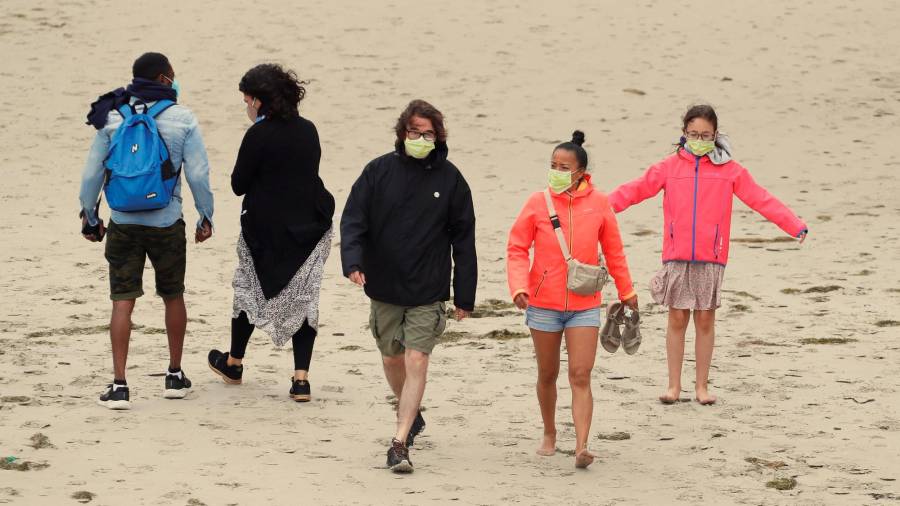 NUEVA NORMALIDAD. Turistas paseando ayer por la playa de As Catedrais con sus mascarillas. Foto: Eliseo Trigo