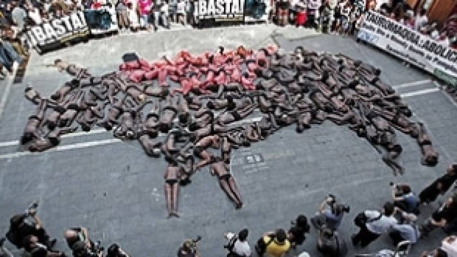 Activistas forman la figura de un toro muerto para mostrar su oposición a los encierros
