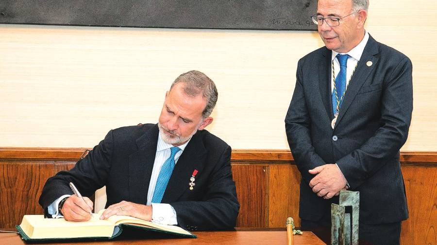 El rey Felipe VI firma en el Libro de Oro de la ciudad ante la atenta mirada del alcalde, Xosé Sánchez Bugallo