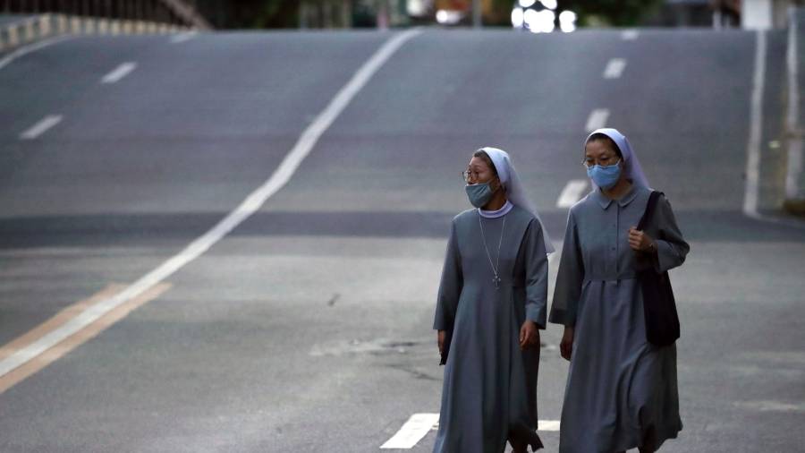Unas monjas, con sus atuendos grises, caminan con la máscara puesta por las calles de Las Pinas en Filipinas. (Autor, Francis R. Malasig. Fuente, EFE)