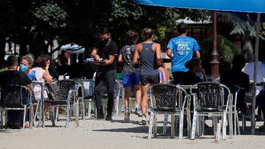 LUGO. Varios corredores pasan entre las mesas de la terraza de un bar mientras practica deporte en el Parque de Rosalía de Castro en Lugo, este martes. EFE/Eliseo Trigo