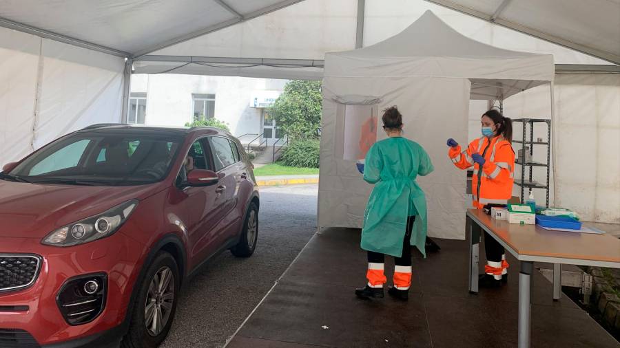 Dos sanitarias realizando las PCR de covid-auto en la entrada del hospital Gil Casares