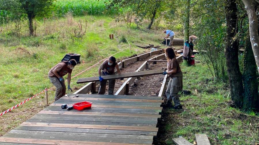 Alumnos del obradoiro de empleo A Laracha V renovando la madera de la pasarela. Autor: CDL