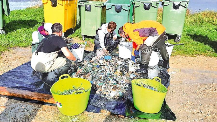 Mariscadores e técnicos da asociación de Baldaio clasificando o lixo recollido. Foto: C. C.
