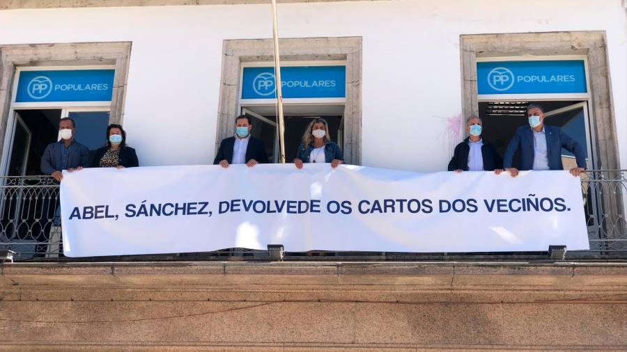 Diputados provinciales del área de Vigo desplegando el cartel en la sede local. Foto: M.Gimeno