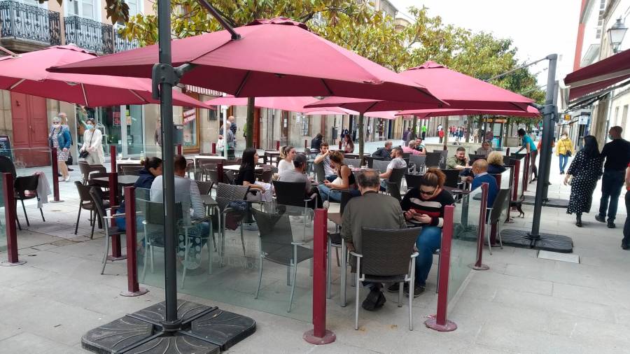 Terraza de una céntrica cafetería en Monforte, con gente en animada charla Foto: Angar