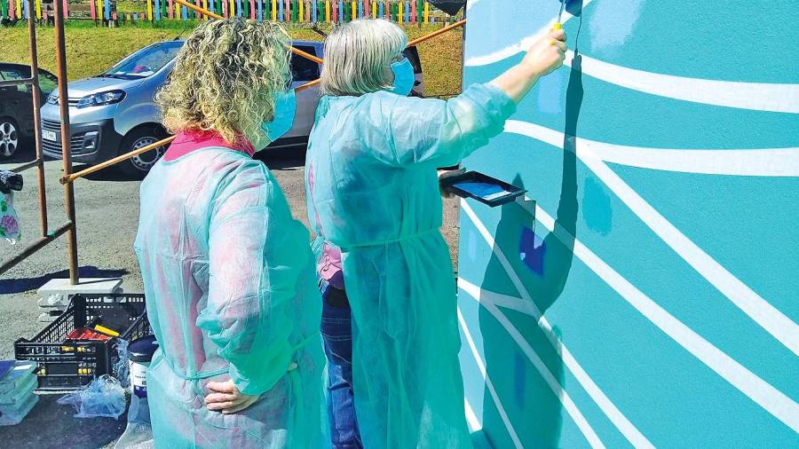 Dos mujeres pintando el exterior del inmueble. Foto: A. S. 