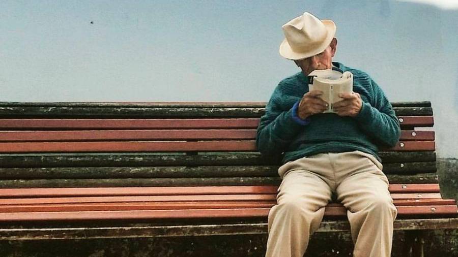 Pensionista leyendo en una calle de Compostela FOTO: ladiapo.com
