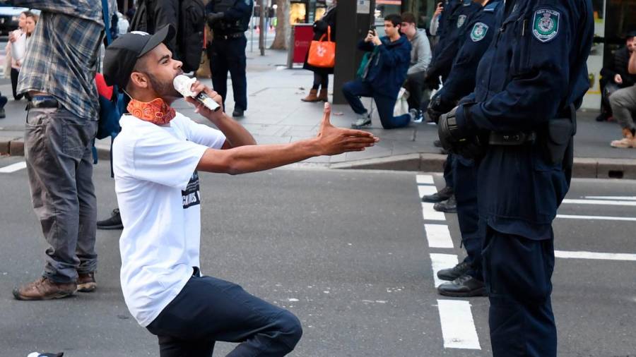 Un manifestante intenta darle la mano a un policía en Sydney. Foto: D. Lewins/Efe