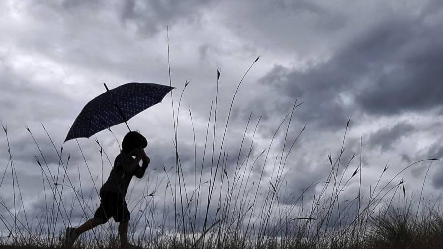 Un niño se resguardaba ayer martes de la lluvia con la ayuda de un paraguas en el concello coruñés de Miño.EFE/ CABALAR