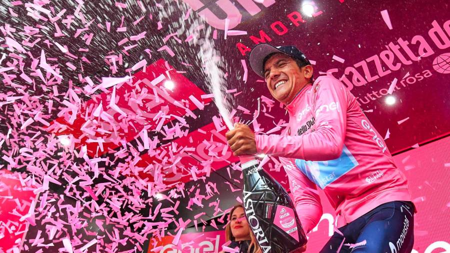 El piloto de motos Richard Carapaz celebra, vestido con el maillot rosa, su victoria para el equipo Movistar tras conseguir el primer puesto en la 14ª etapa de la edición 102 del Giro de Italia. (Autor, Akhtar Soomro. Fuente, EFE)