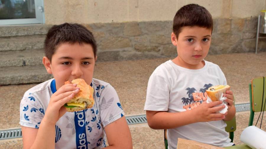 Dous nenos da Escola de Verán de Valga degustan un bocata de sardiñas, queixo e vexetais. Foto: C. Valga