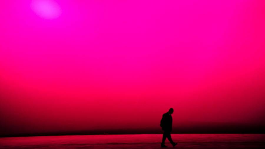 Un hombre camina por las calles de Brasil con el edificio del congreso tintado de rosa como telón de fondo. (Autor, Akhtar Soomro. Fuente, EFE)