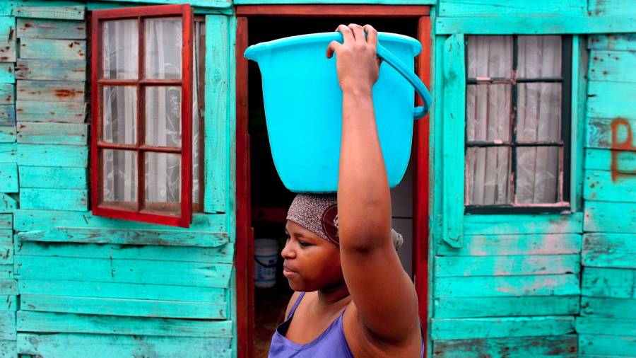 Una estudiante sudafricana transporta agua en su cabeza desde una fuente pública a casa de sus padres. Esta fotografía fue tomada en Cape Town, Sudáfrica, en el año 2008. (Autor, Nic Bothm. Fuente, EFE)