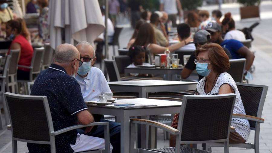 Foto de archivo de personas con mascarilla consumiendo en una terraza. EFE