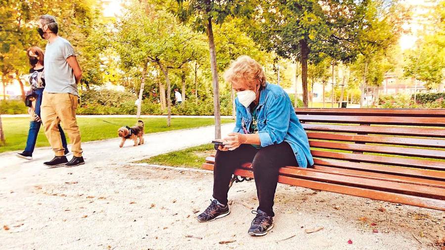 Una jubilada descansa en un parque público mientras observa su teléfono móvil. Foto: E.P.