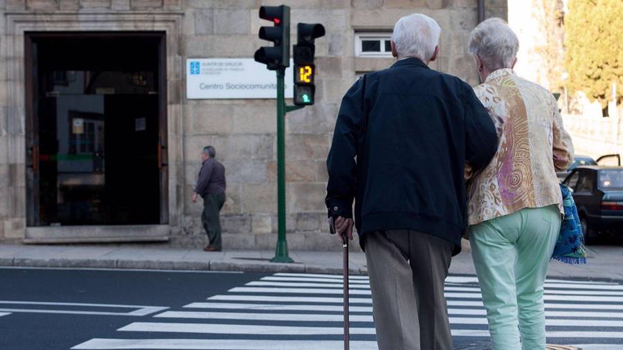 Na foto de arquivo, dúas persoas cruzan a rúa cara o centro sociocomunitario Porta do Camiño, en Santiago. XUNTA