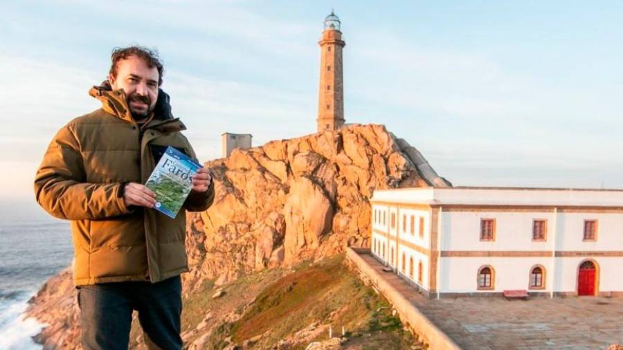 Rafael Lema, al pie del faro de cabo Vilán, con un ejemplar del libro ‘Camiño dos Faros’. Foto: Guíaburros Editatum