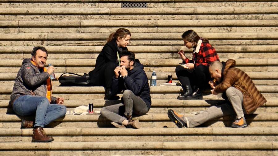 Personas comiendo ayer en la calle ante la imposibilidad de hacerlo en un restaurante. Foto: Fernando Blanco