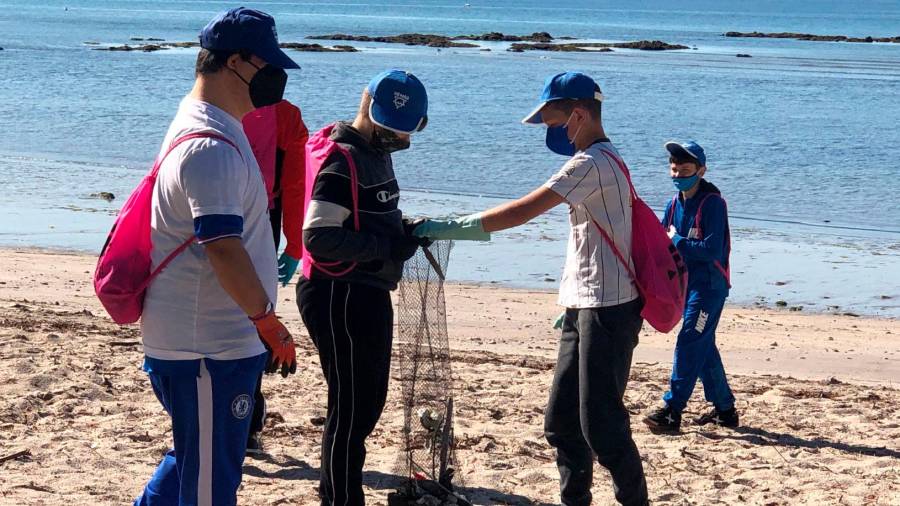 INTEGRACIÓN. Escolares de Boiro y usuarios de Amicos, recogiendo residuos en el arenal de Praia Xardín.