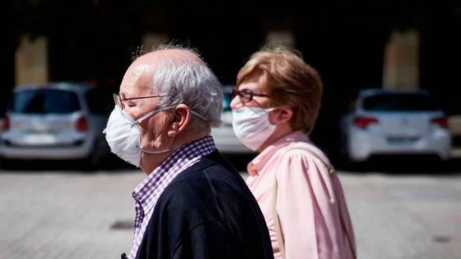 Una pareja de personas mayores caminan por la calle usando mascarilla. Foto: Europa Press