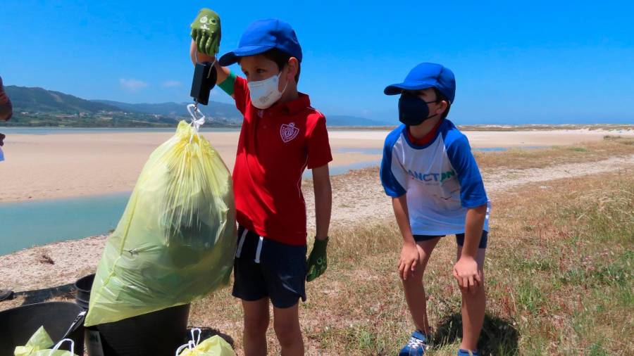 Uno de los niños que acudieron a Razo pesando una bolsa llena de residuos recogidos en el arenal carballés.