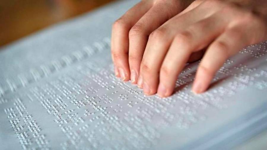 Unha persoa cega le nun texto en braille. Foto: ONCE